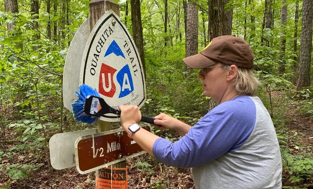 volunteer cleaning a trail sign